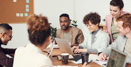 Équipe de professionnels en ressources humaines discutant de la fusion-acquisition et de l'intégration post-fusion autour d'une table.