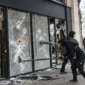 Individus masqués brisant la vitrine d'un commerce lors d'un pillage